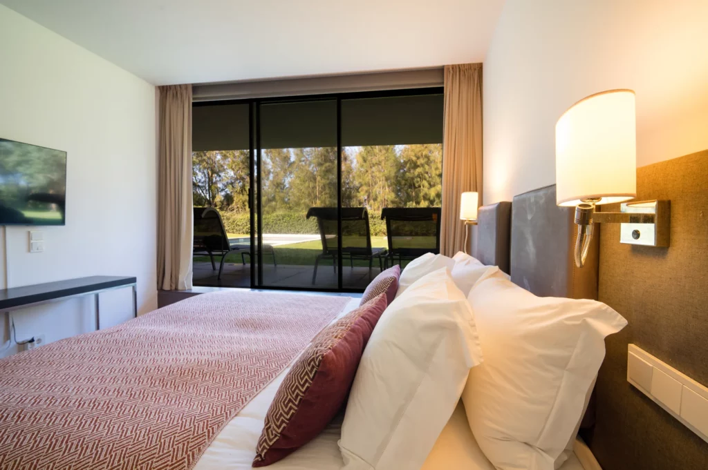 Dormitorio en suite de la villa con vistas y salida directa al jardín y a la piscina